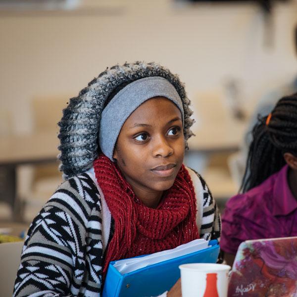 A history major student leans forward and listens in class.
